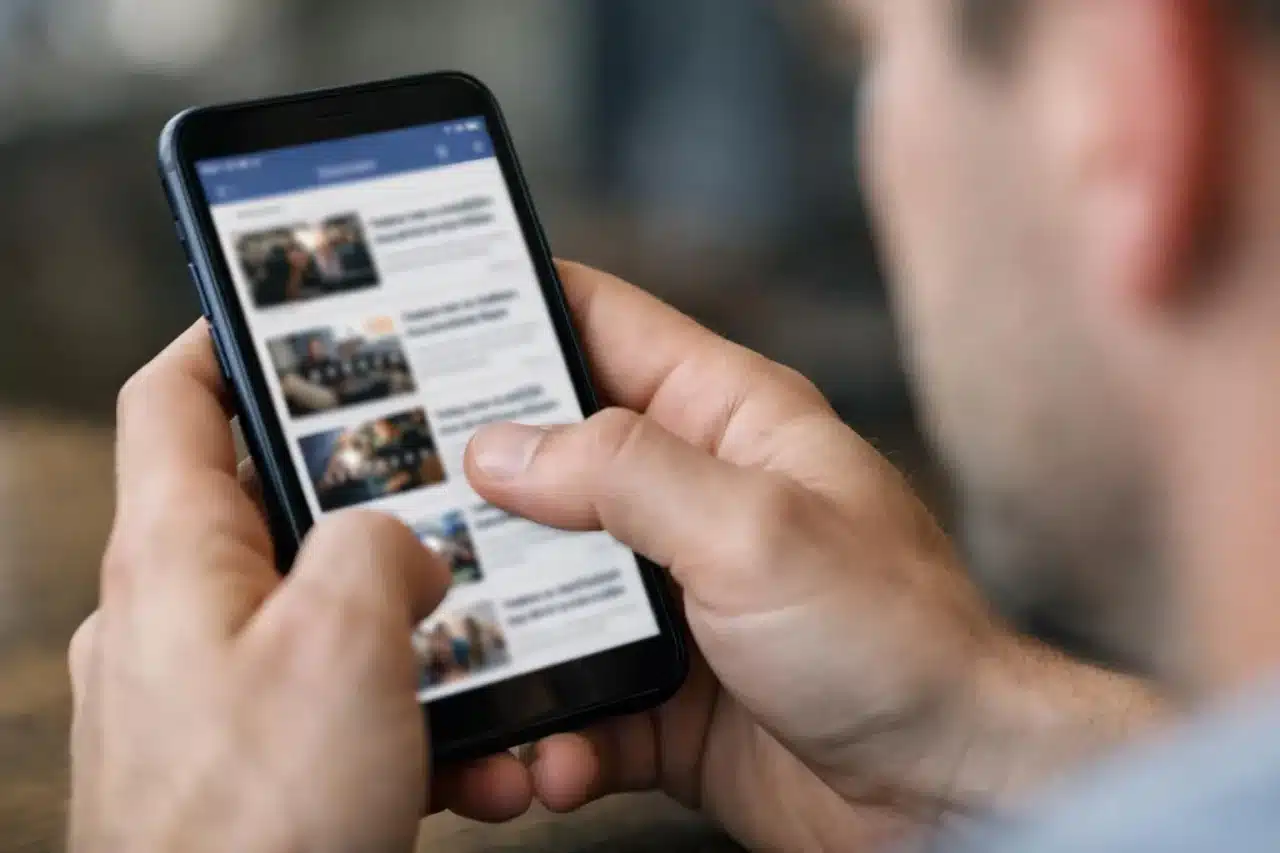Actualité sociale sur smartphone cette semaine, mains tenant un téléphone avec fil d'actualité