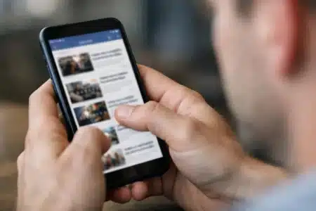 Actualité sociale sur smartphone cette semaine, mains tenant un téléphone avec fil d'actualité