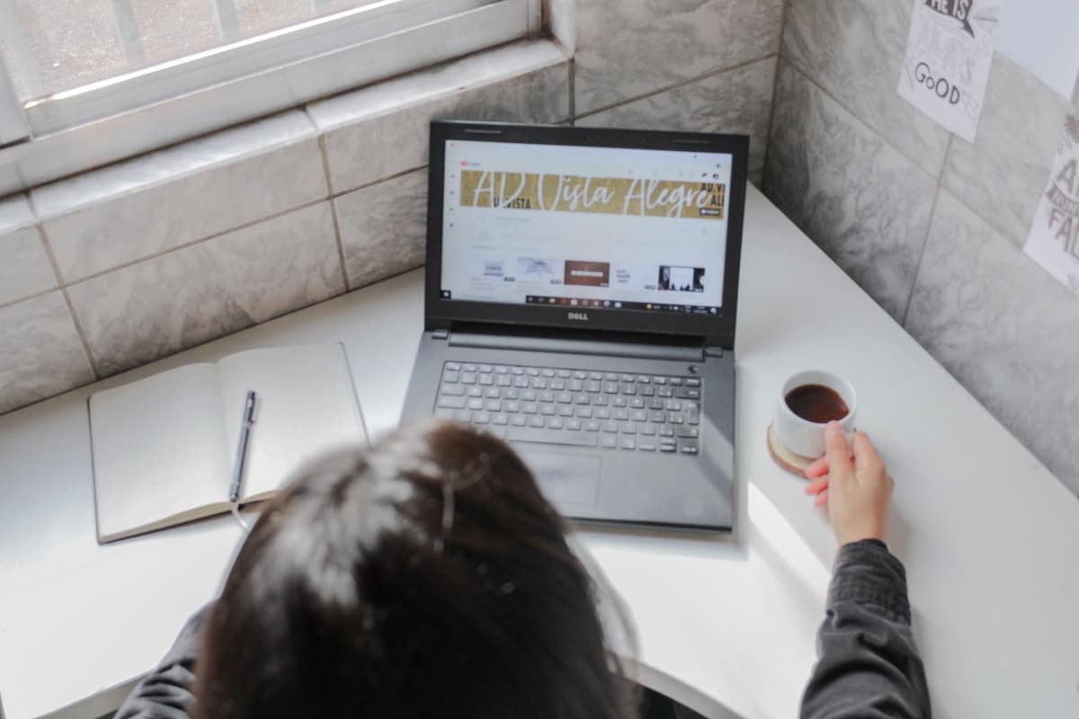 Une personne en chemise noire à manches longues tenant une tasse en céramique blanche.