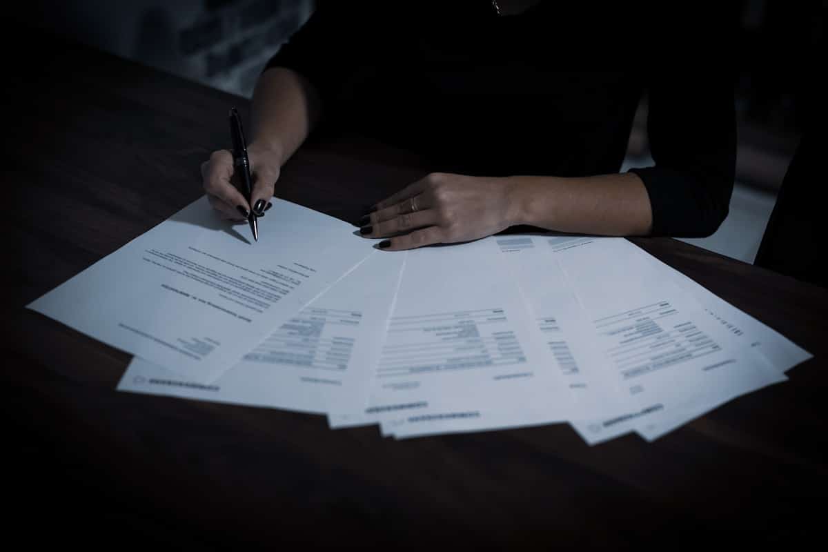 Mains signant des documents dans un environnement sombre et mystérieux.