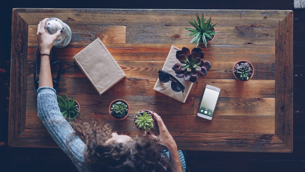 Une femme arrange des plantes sur une table en bois.
