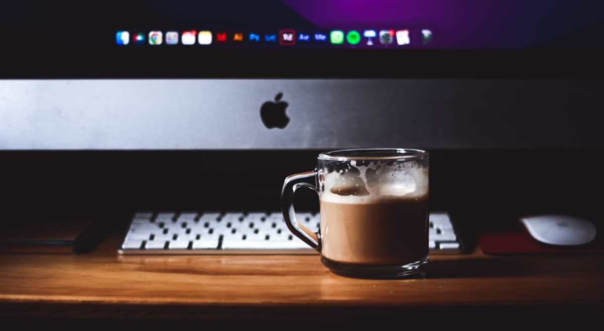 Tasse de café sur un bureau avec clavier d'ordinateur et logo Apple.