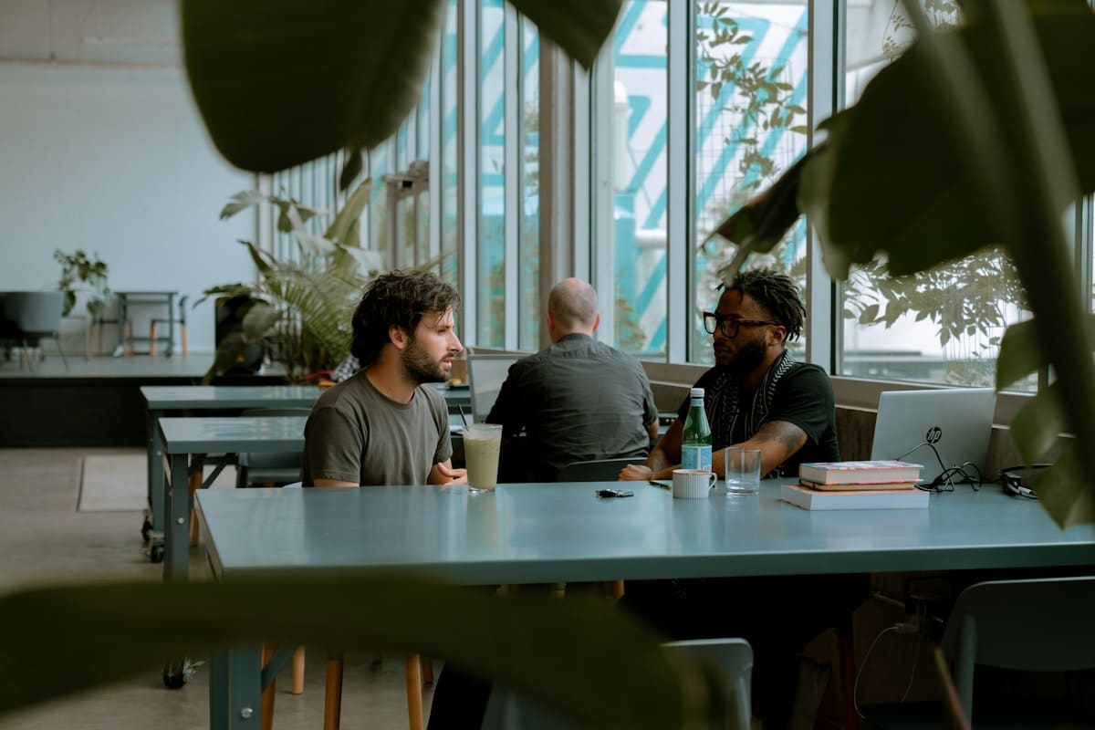 Trois hommes assis à une table dans un espace de travail moderne.
