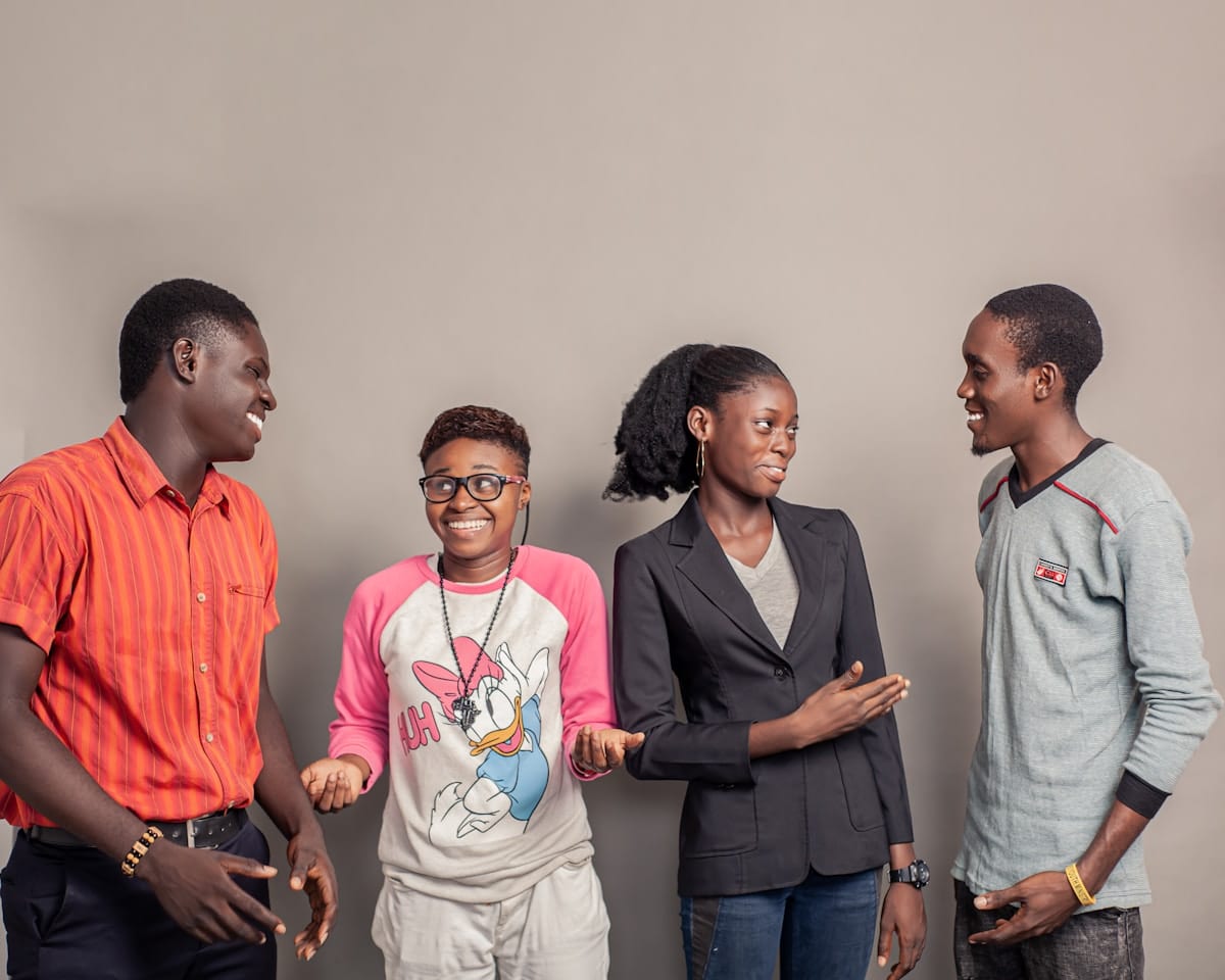 Quatre jeunes personnes africaines, souriantes et habillées de manière décontractée.