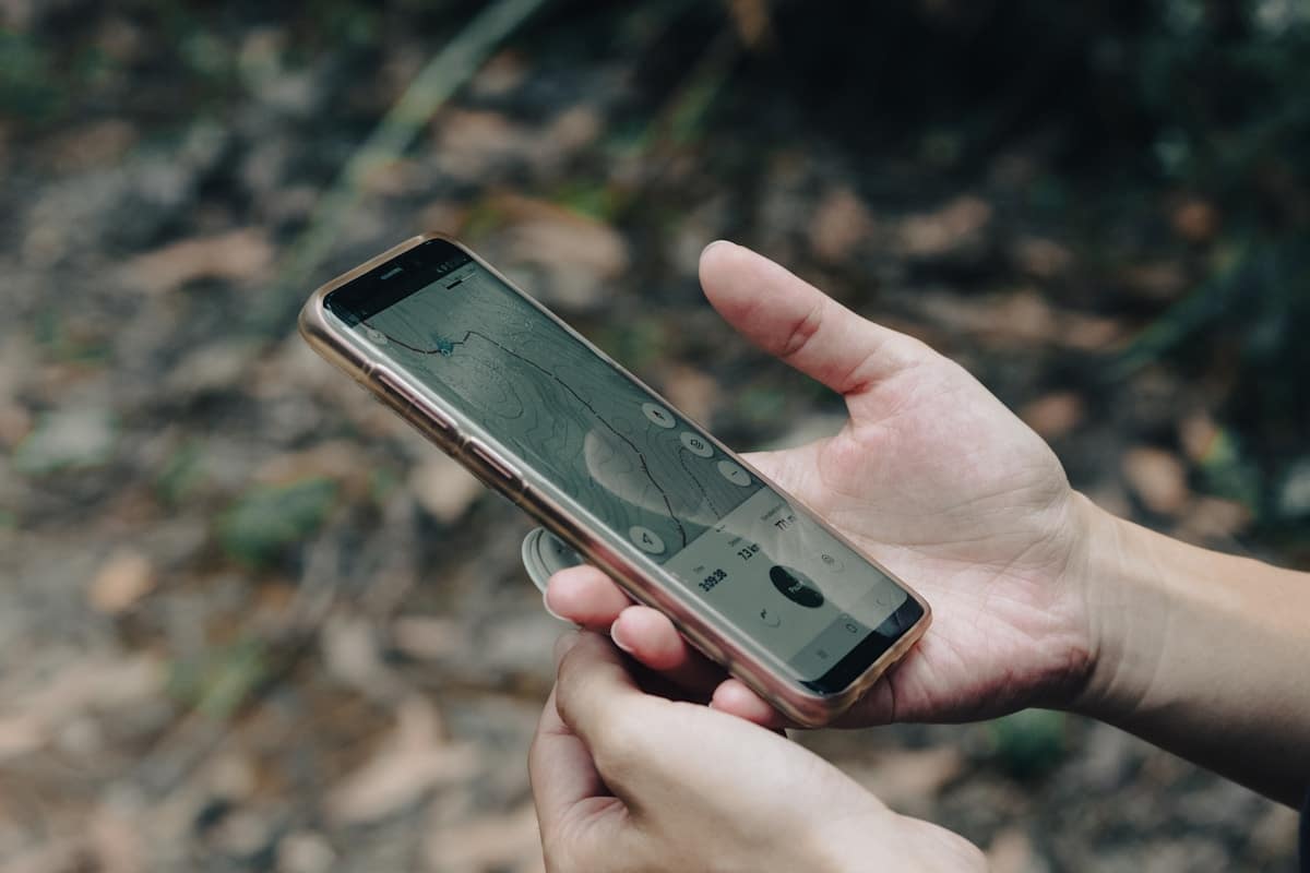 Smartphone affichant une application de navigation dans un environnement forestier.