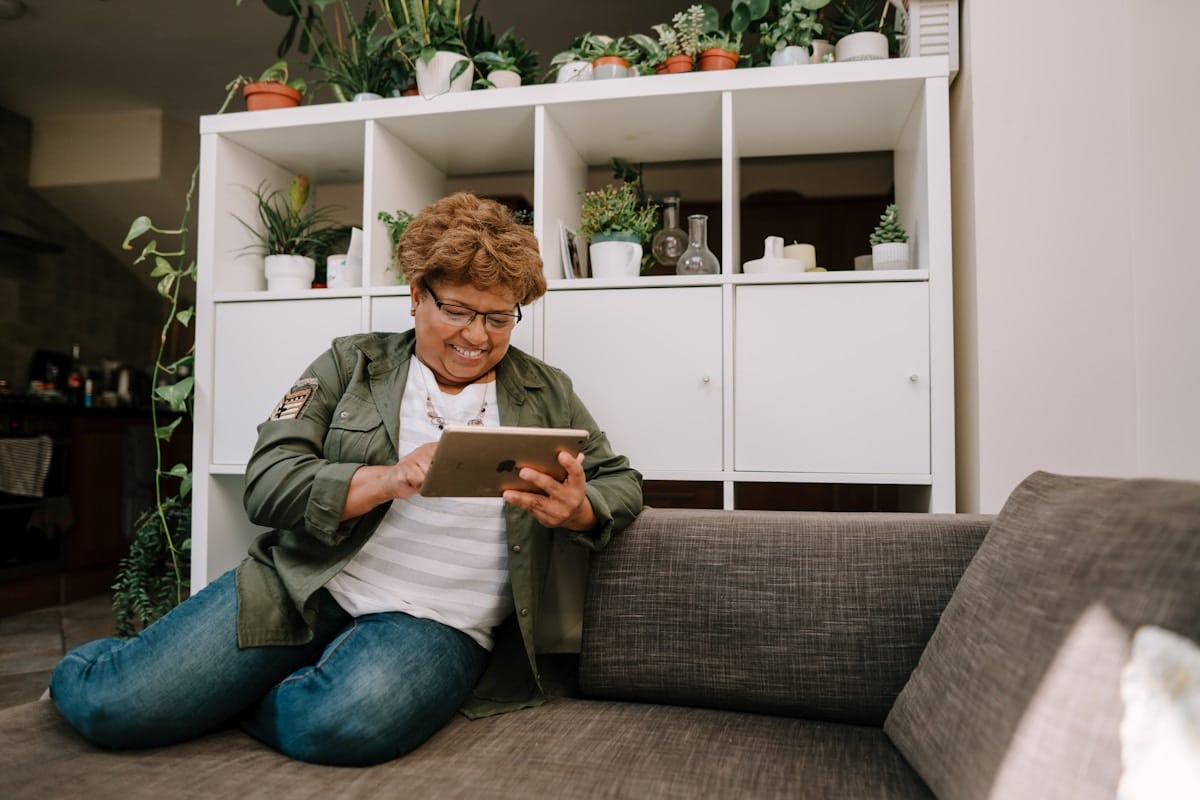 Une femme assise sur un canapé regardant une tablette.