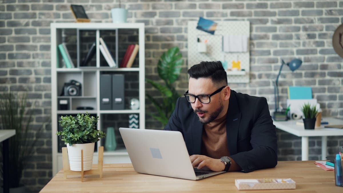 Homme d'affaires concentré travaillant sur un ordinateur portable dans un bureau moderne.