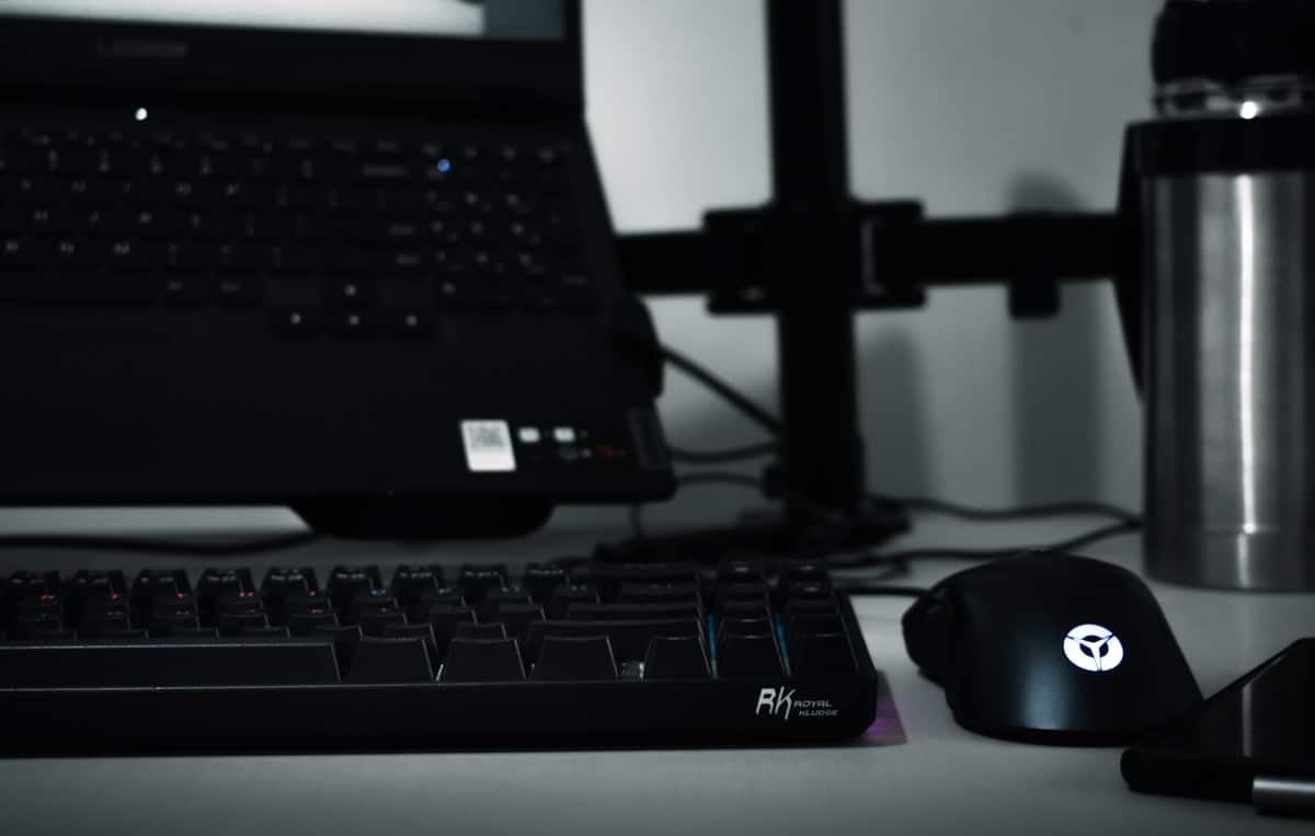 Clavier, souris et ordinateur portable dans une atmosphère sombre et monochromatique.