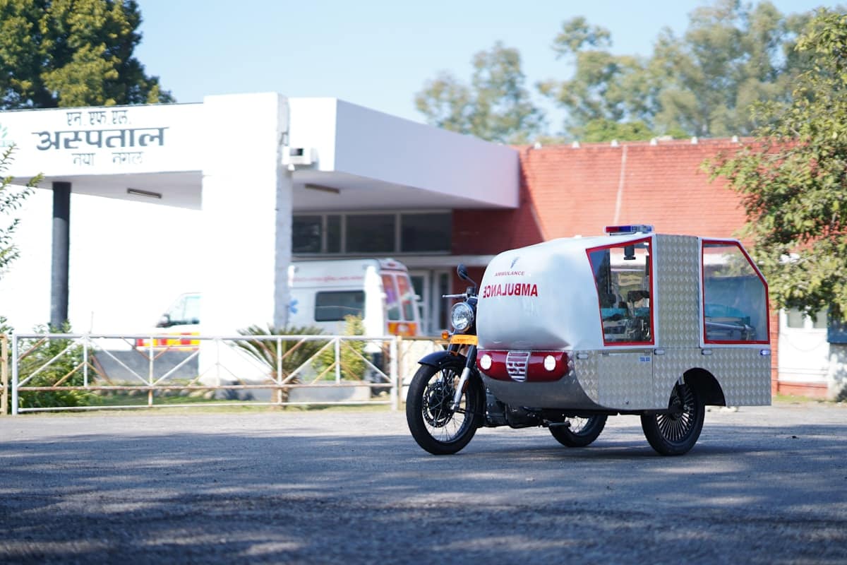 Ambulance tricycle devant un bâtiment médical.