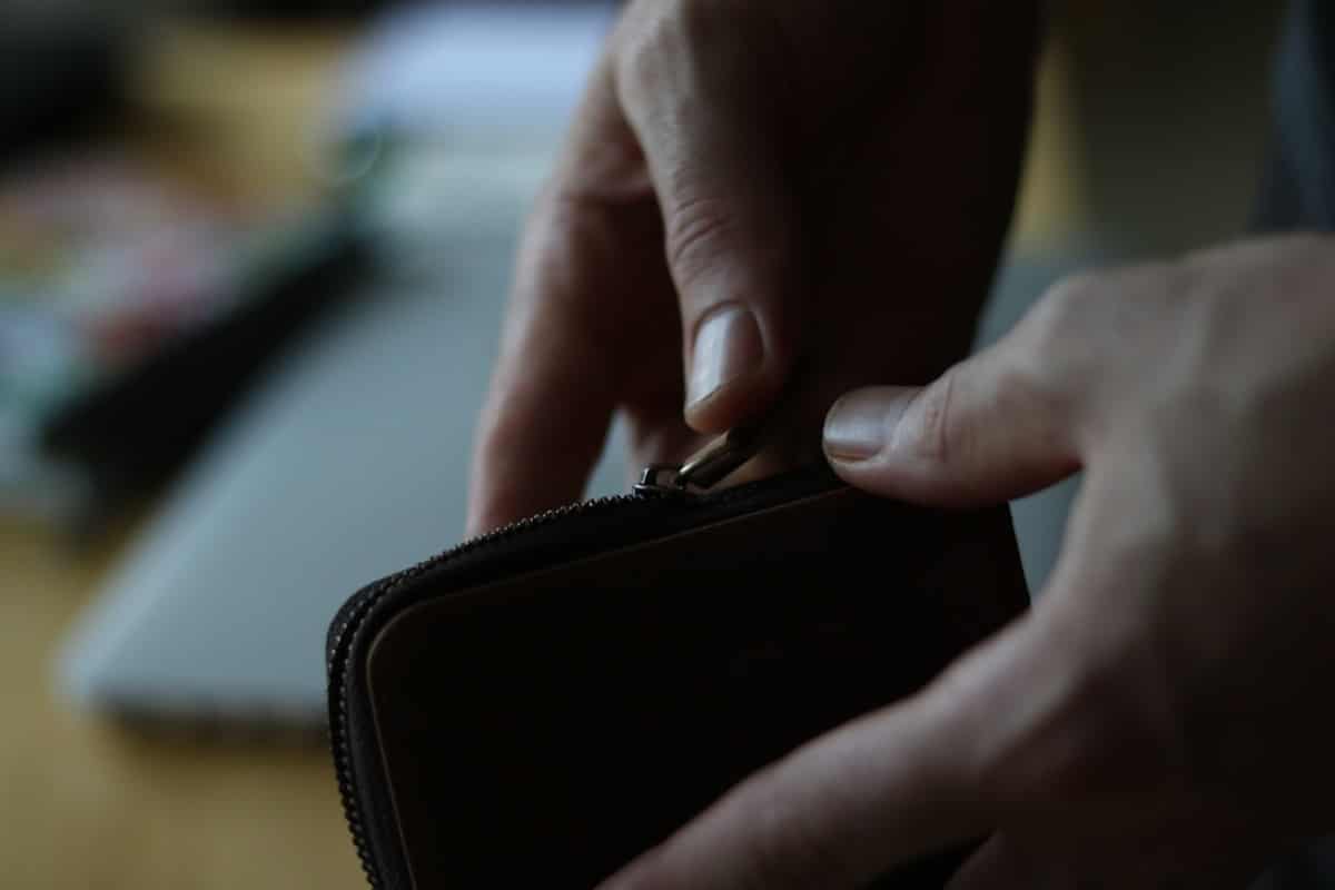 Mains ouvrant un portefeuille en cuir noir.