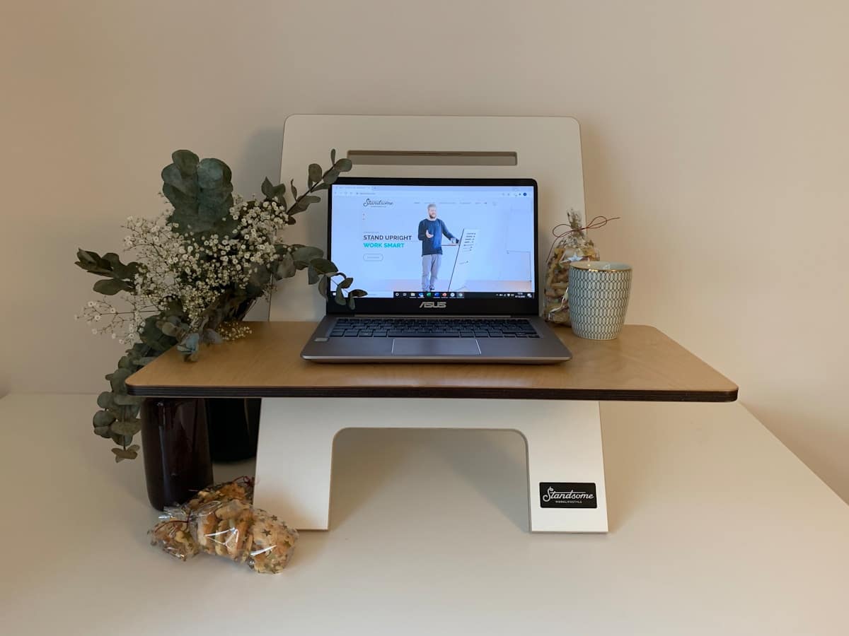 Bureau de travail avec ordinateur portable, fleurs et collation.