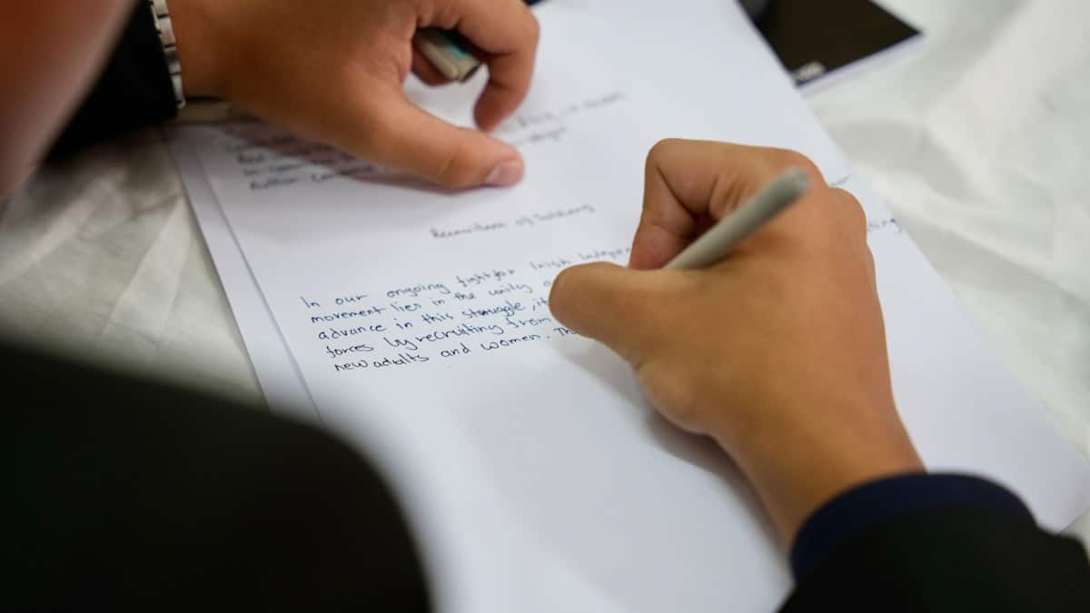 Mains écrivant sur un document avec un stylo.