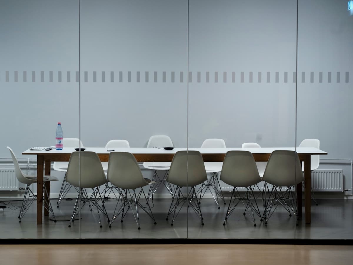 Salle de réunion avec table en bois et chaises grises.