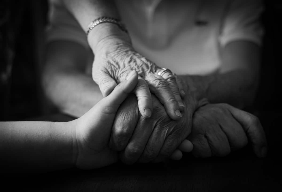 Mains âgées tenant tendrement les mains d'un être cher.