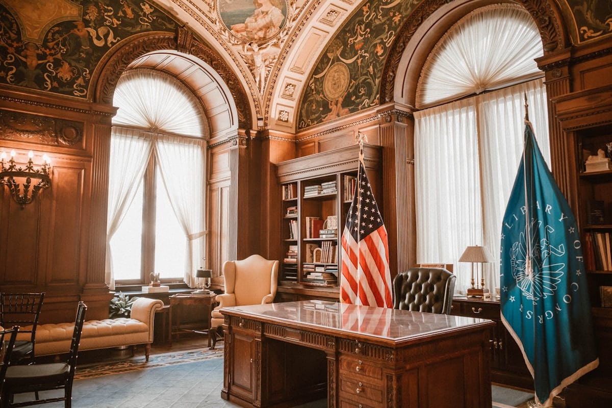 Salle de bureau ornée de décorations luxueuses, avec drapeau américain et meuble imposant.