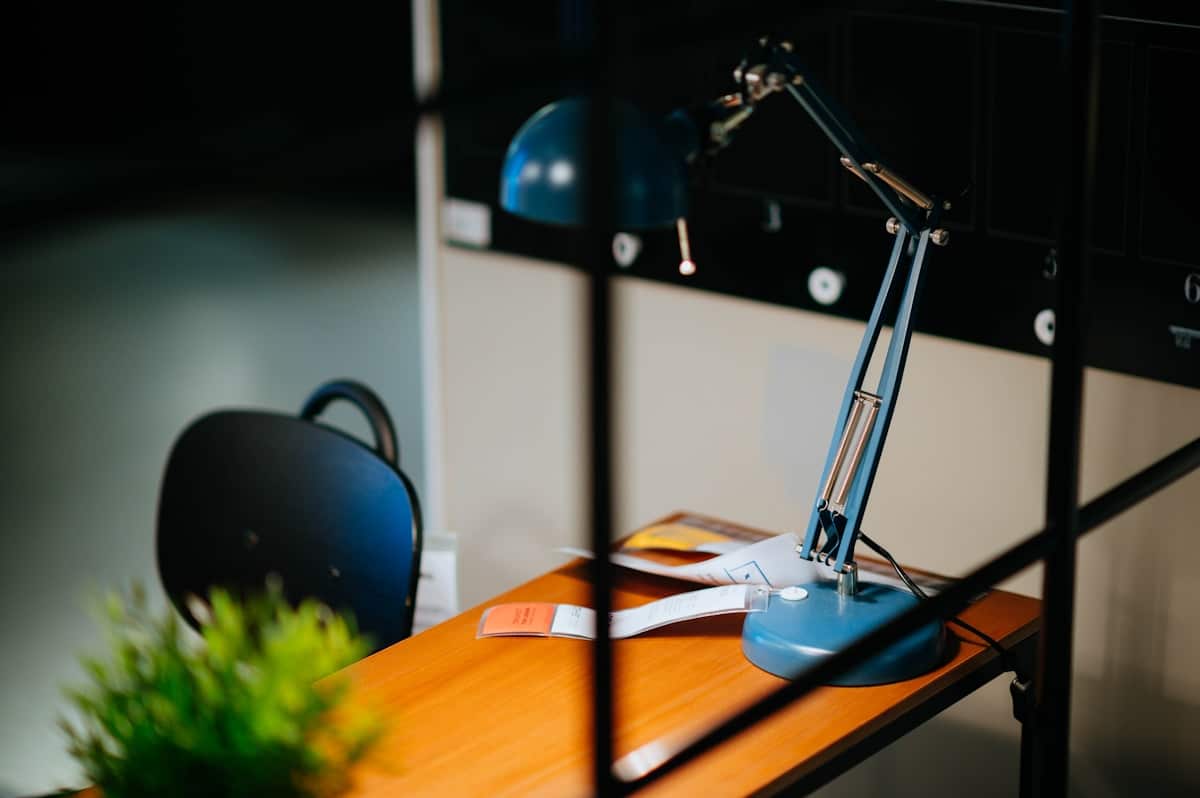 Bureau de travail avec lampe de bureau bleue et accessoires.