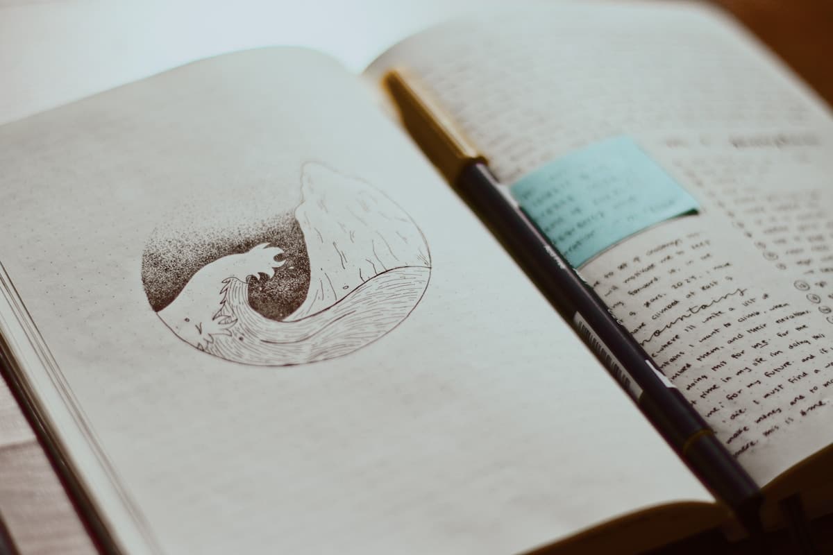 Carnet ouvert avec un dessin de poisson et un stylo.