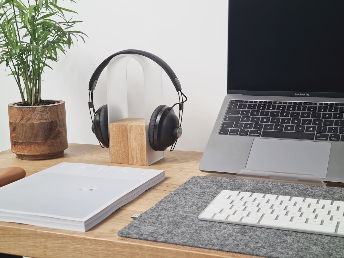 Bureau de travail avec ordinateur portable, casque audio et accessoires.