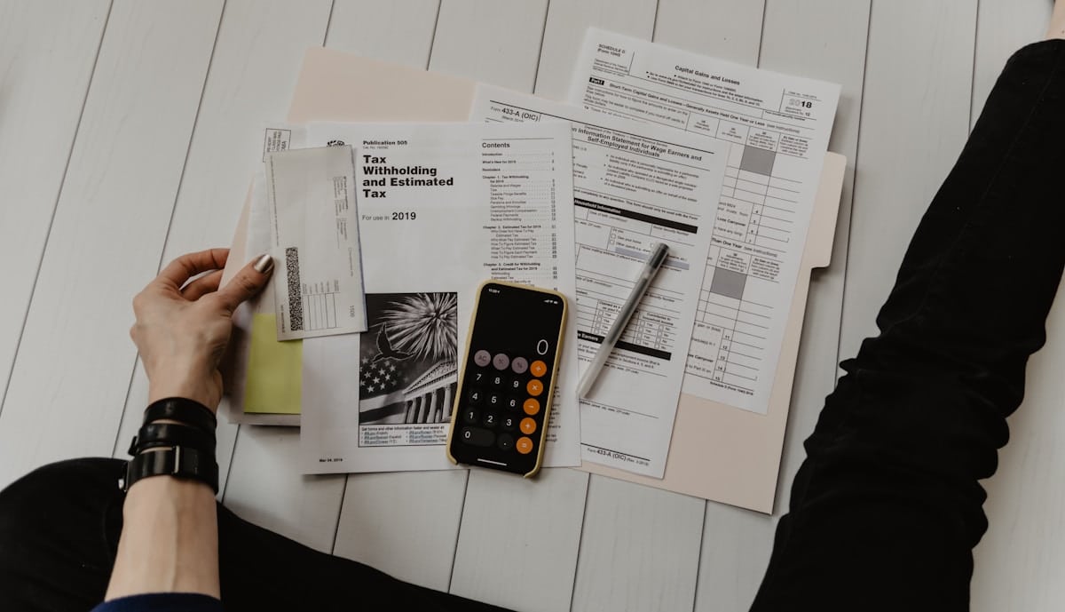 Documents fiscaux, calculatrice et stylo sur une surface en bois.
