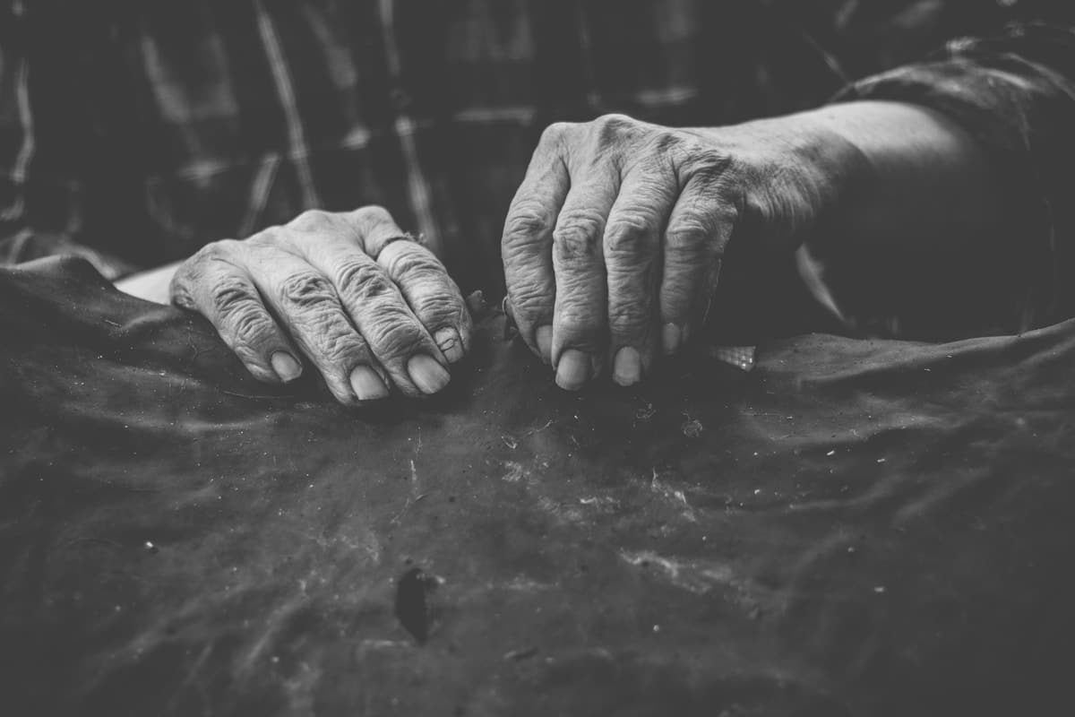 Mains âgées, ridées, agrippées à une surface rugueuse.