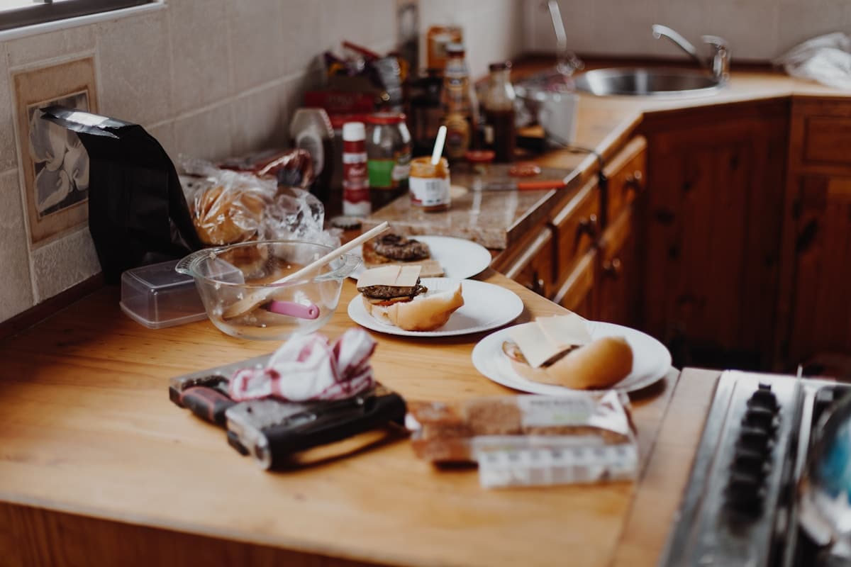 Cuisine désordonnée avec restes de nourriture et ustensiles éparpillés.