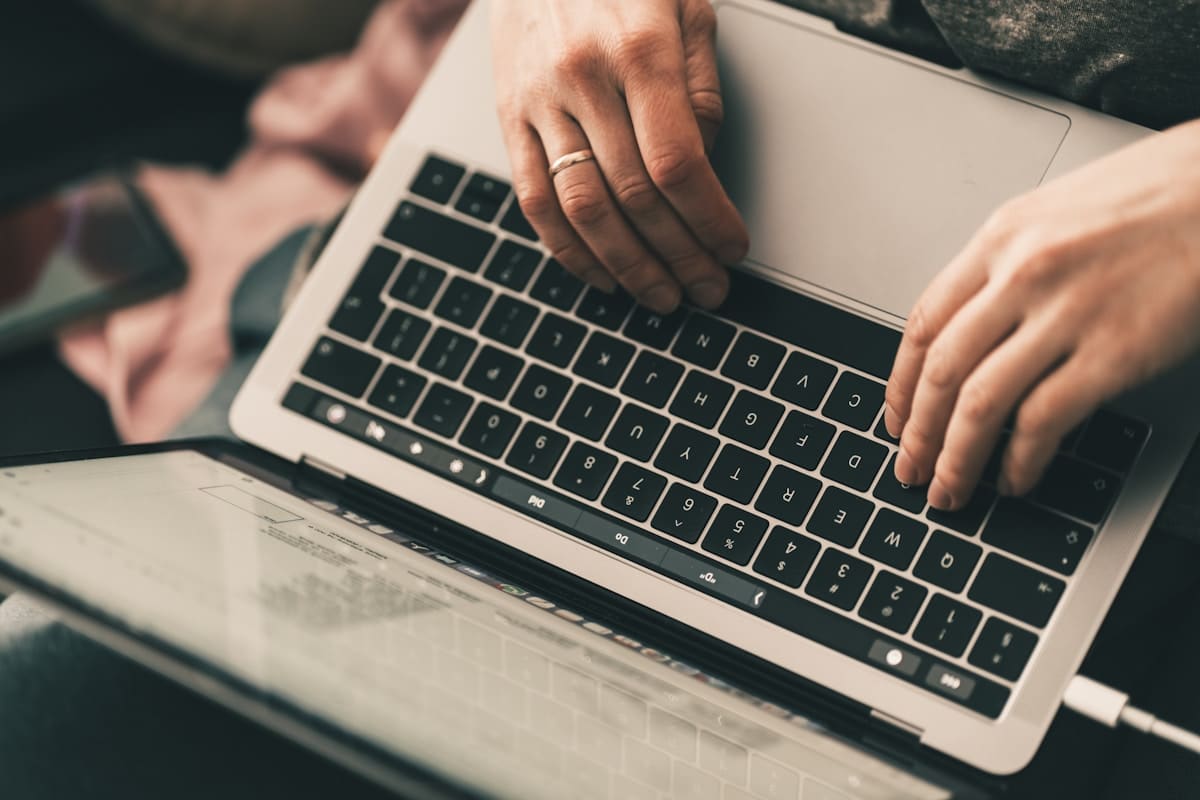 Mains tapant sur un clavier d'ordinateur portable dans un environnement sombre.