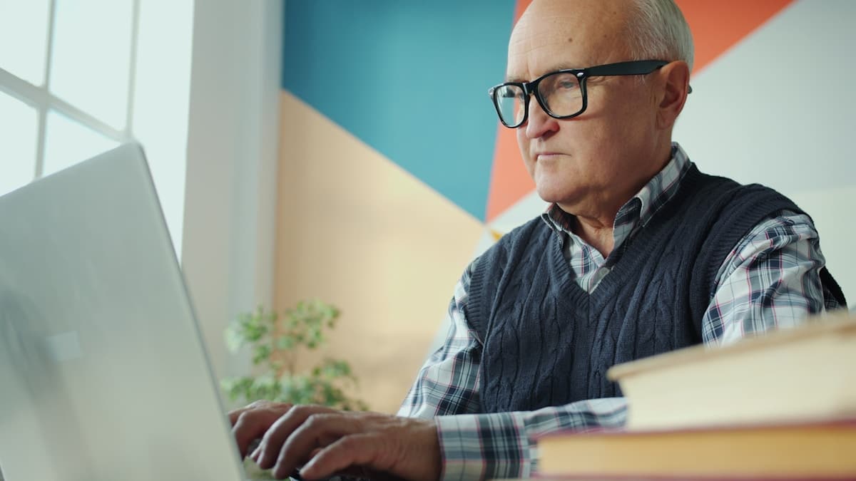 Un homme âgé travaillant sur un ordinateur portable dans un bureau.
