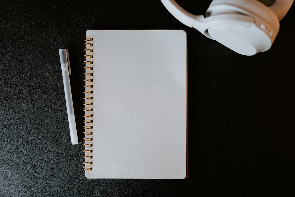 Cahier à spirale blanc avec un stylo blanc sur un fond noir.